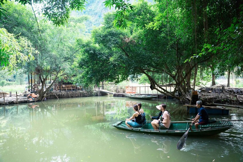 A group of people in a green boat on a calm river surrounded by lush greenery and trees. 4