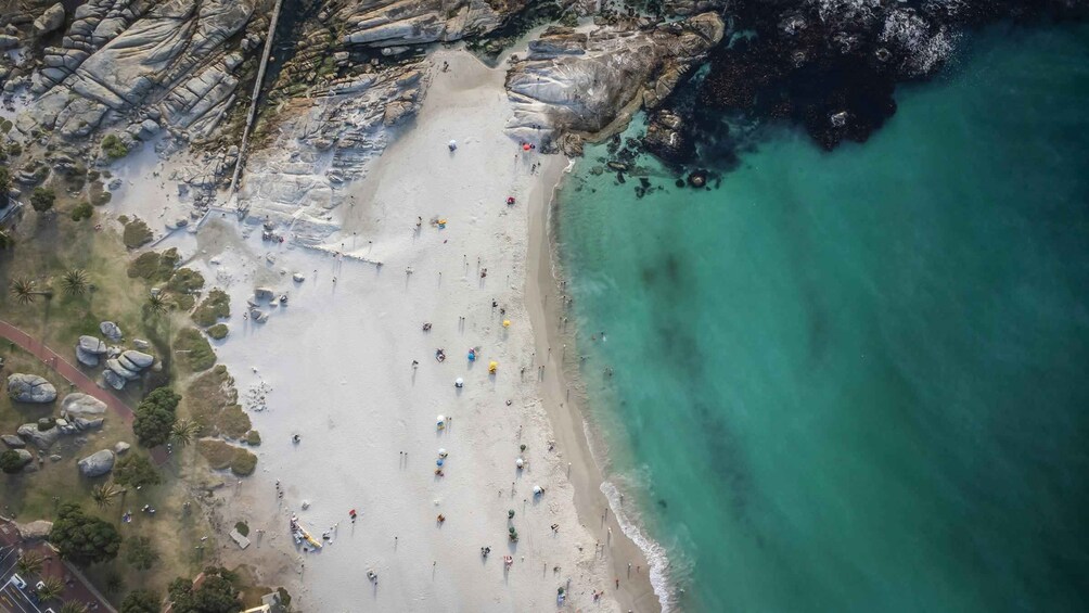 Luchtbeeld van een strand met mensen, parasols en rotsen. 3