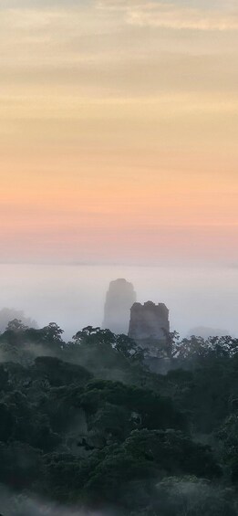 A foggy landscape with a prominent rock formation in the distance. 4
