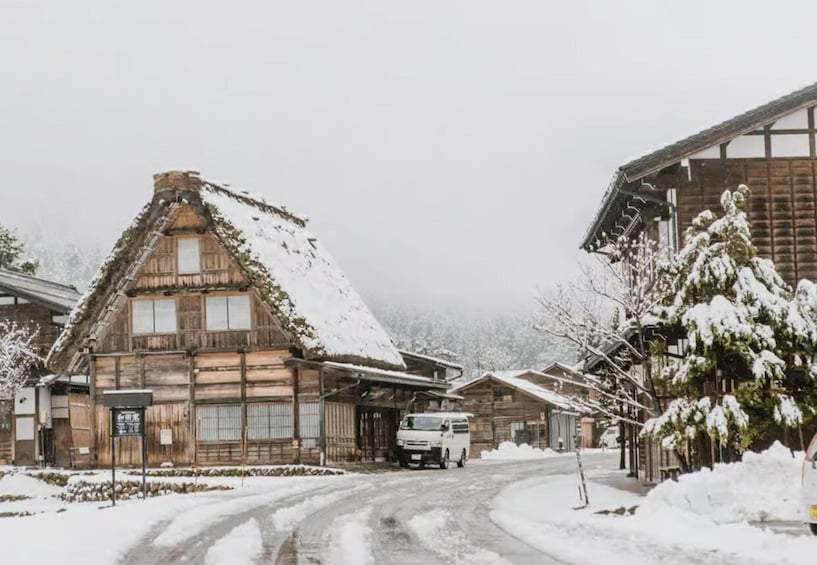 A snow-covered village with traditional wooden houses and a van parked in front. 3