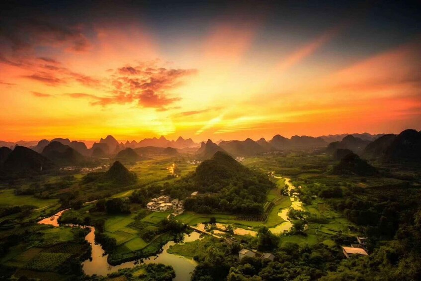 A landscape with a river, green fields, and mountains during sunset. 2