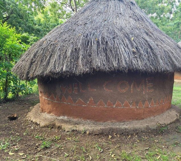 A traditional thatched hut with 'WELCOME HOME' carved into its side. 4