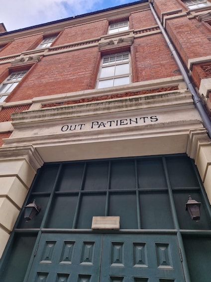 A building facade with a sign reading "OUT PATIENTS" above a green door. 5
