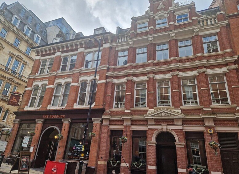A red brick building with ornate detailing and a sign for 'The Roebuck' pub. 1
