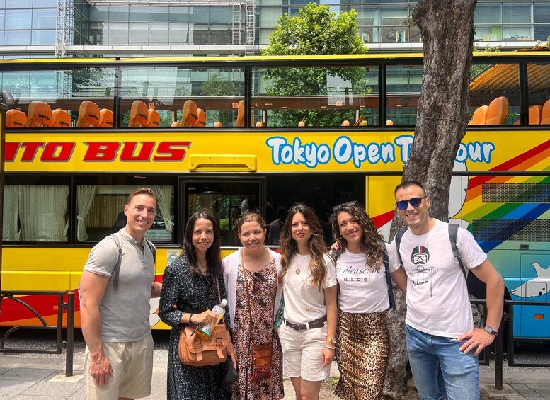 A group of people standing in front of a double-decker bus with 'Tokyo Open Tour' written on it. 3