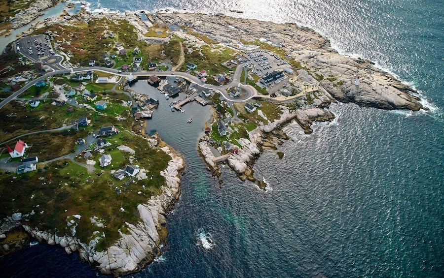 An aerial view of a coastal town with houses, a road, and a rocky shoreline. 5