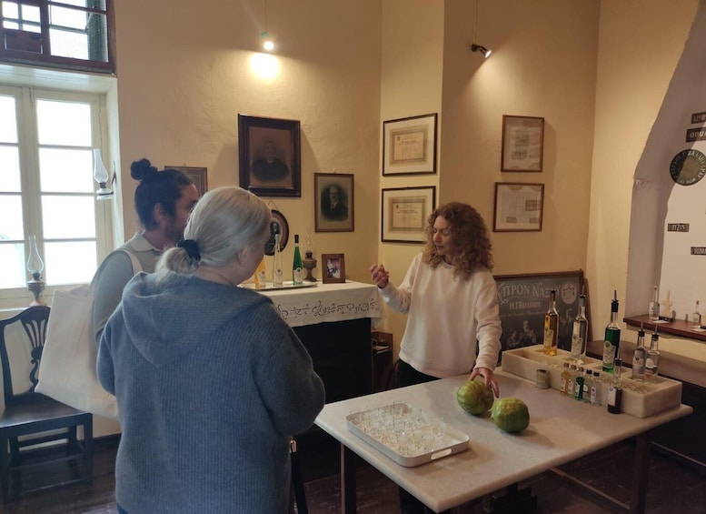 A group of people in a room with a table displaying bottles and a tray of glasses. 2