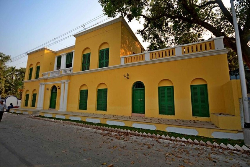 A yellow building with green shutters and a white balcony. 4