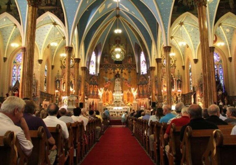A church interior with a red carpet aisle, wooden pews, and a central altar. 2
