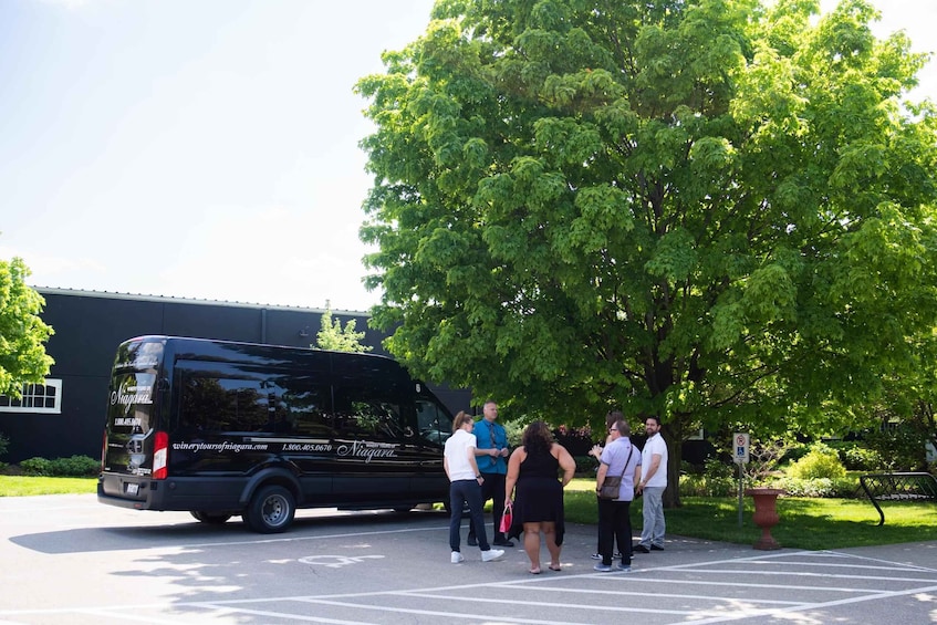 A black van parked in a parking lot with people standing around it. 5