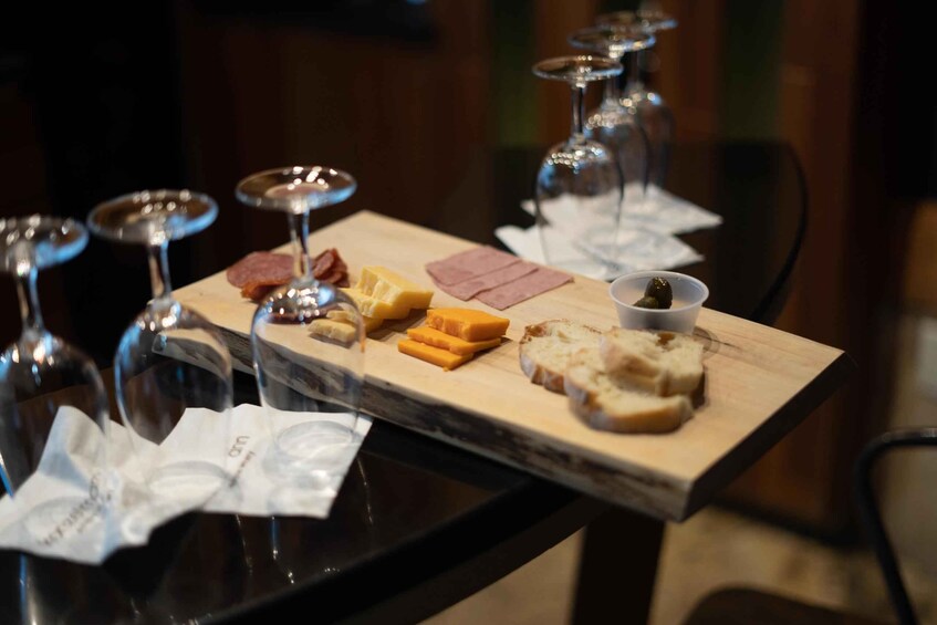 A charcuterie board with various cheeses, meats, and bread, accompanied by wine glasses. 1