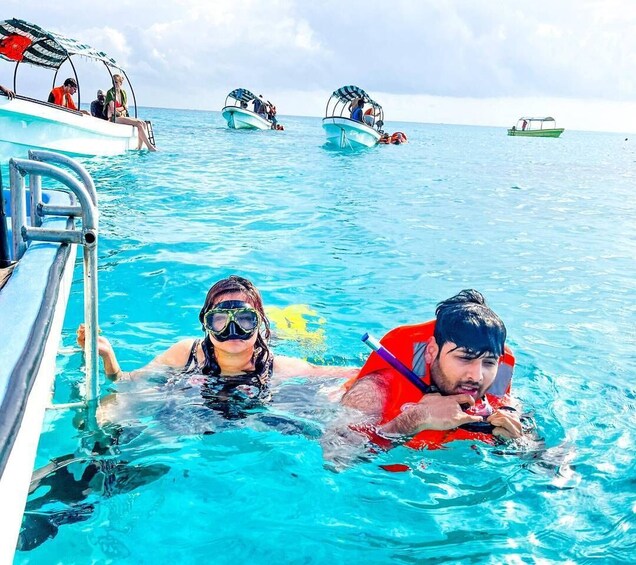 Dos personas nadando en una piscina azul cristalina, con barcos al fondo. 5