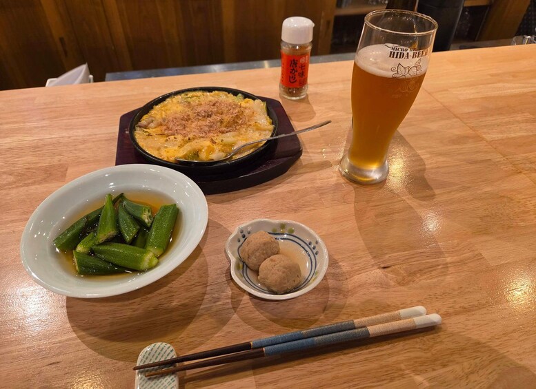 A meal with okra, dumplings, and a beer glass on a wooden table. 3