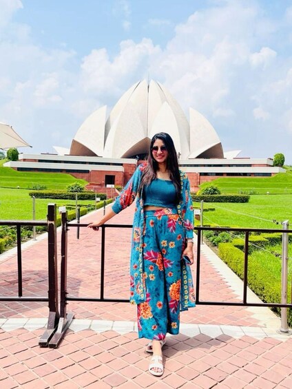 A person standing in front of a large white building with a unique architectural design. 2