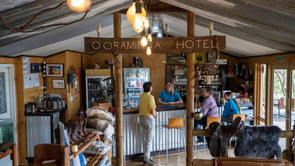 A rustic interior of Ooraminia Hotel with wooden decor, a bar area, and a visible refrigerator. 3