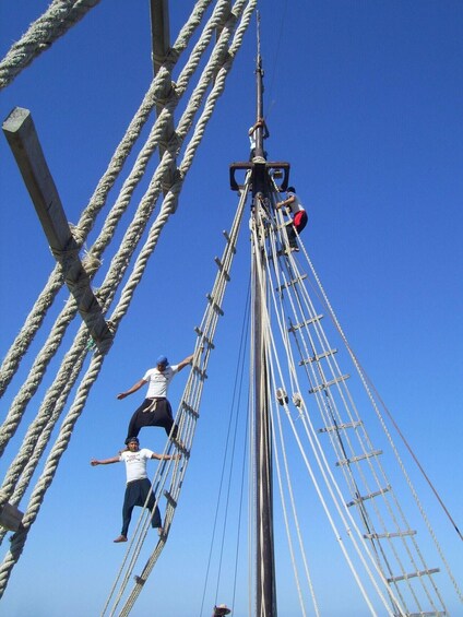 Two people climbing a ship's rigging. 3
