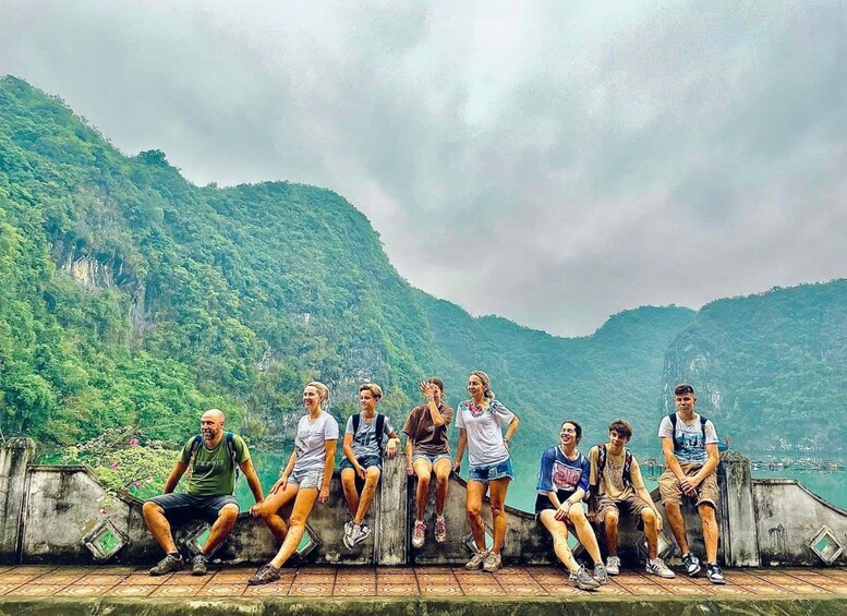 A group of people sitting on a ledge overlooking a mountainous landscape. 1