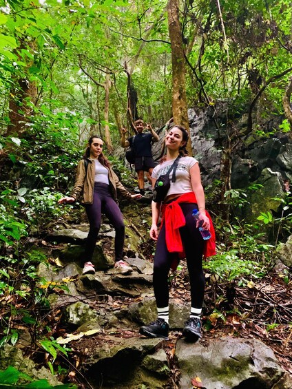 Three people hiking on a rocky trail in a dense forest. 5