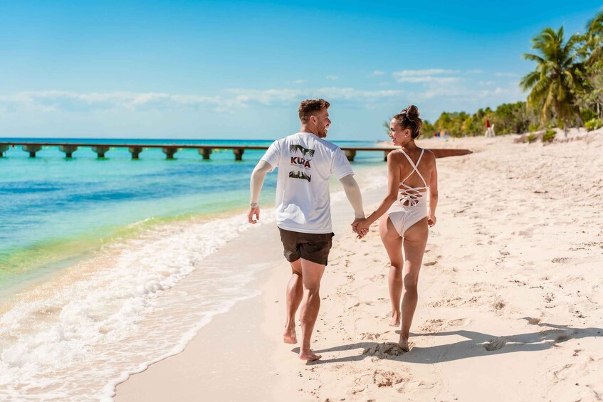 A couple walking on a sandy beach with a clear blue sky and a pier in the background. 5