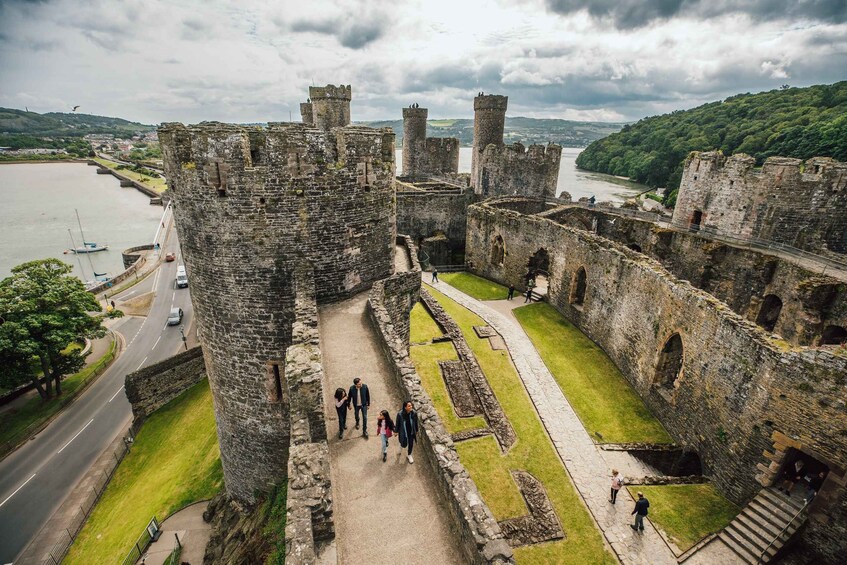 A historic castle with a moat, surrounded by greenery and a river. 1