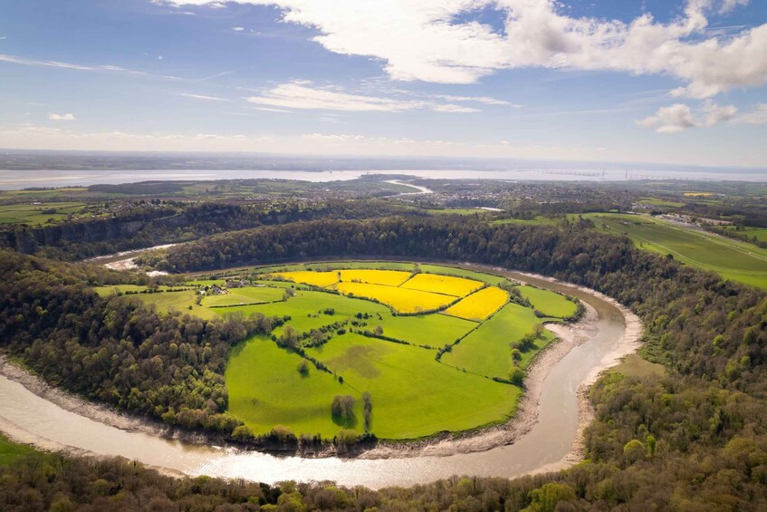 A river winding through a green landscape with yellow fields and a bridge in the distance. 5