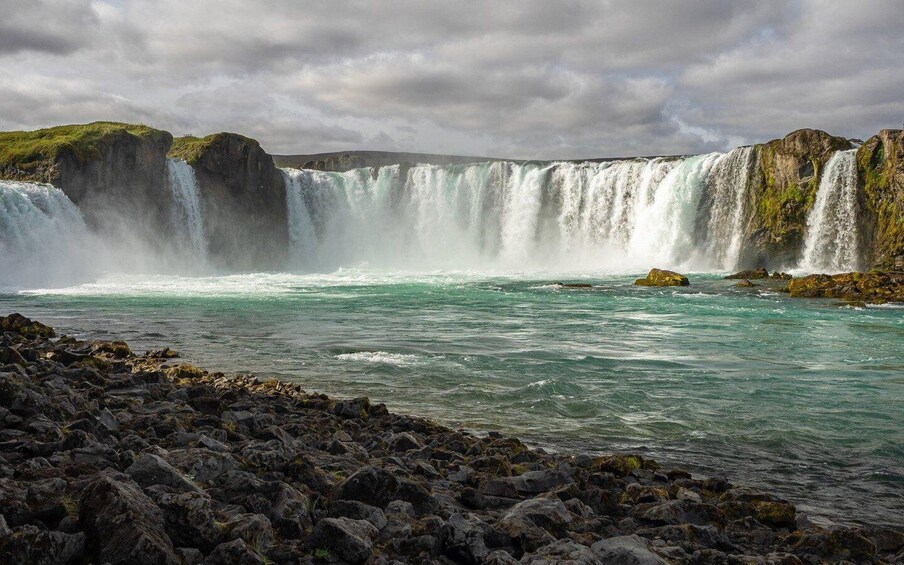 A large waterfall with multiple cascades, surrounded by rocky terrain and ocean waves. 5