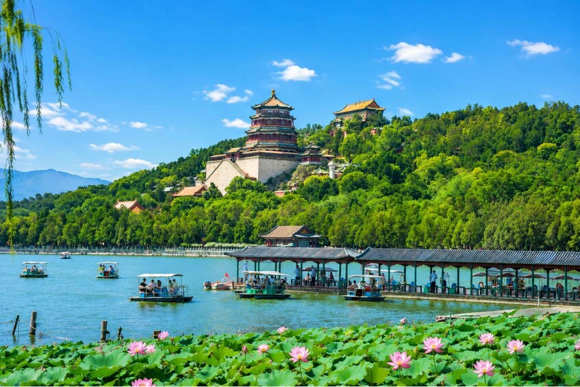 A traditional pagoda on a hill, a lake with boats, and lotus flowers in the foreground. 1