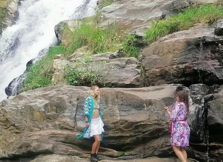 Two people standing on rocky terrain near a waterfall. 4