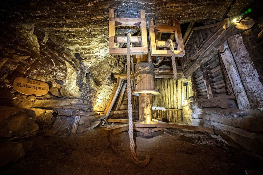 An underground wooden structure with a pulley system, wooden walls, and a sign. 2