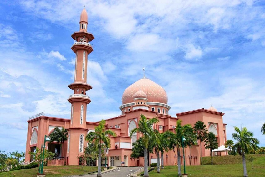 A mosque with a tall minaret and a large dome, surrounded by palm trees and a clear sky. 4