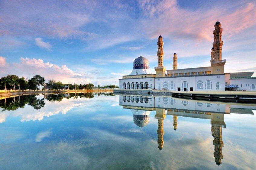 A mosque with a large dome and two minarets, reflecting in a calm body of water. 3