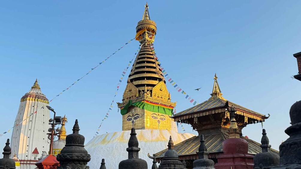 Suuri stupa, jonka huipulla on kultainen torni, ja jonka ympärillä on pienempiä rakennelmia ja rukolippuja. 5