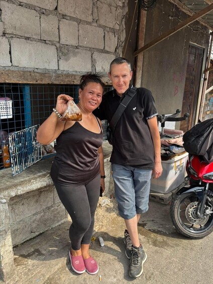 Two people standing in front of a building with a motorcycle parked nearby. 5