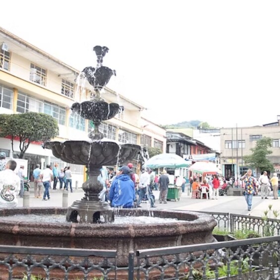 A public square with a central fountain, surrounded by buildings and people. 2