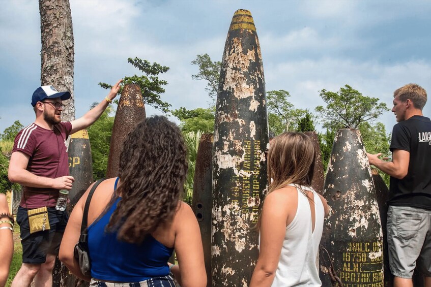 A group of people observing large, weathered stone pillars with inscriptions. 4