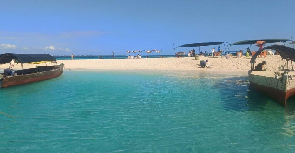 A beach with clear turquoise water, boats anchored near the shore, and people relaxing under umbrellas. 5
