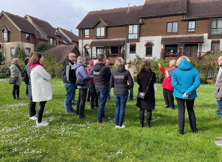 A group of people standing on a grassy field in front of a row of houses. 2