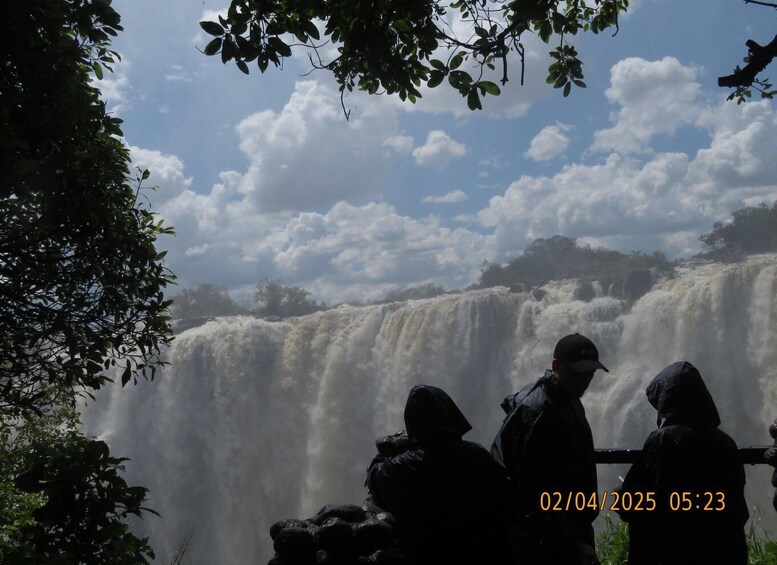 A waterfall with people observing it. 1
