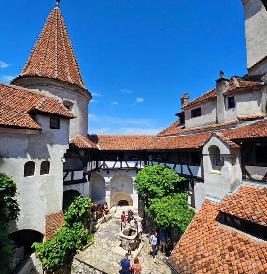 A historic courtyard with tiled roofs, stone walls, and a central fountain. 2