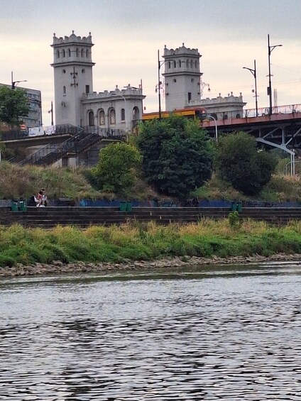 A river with a castle-like structure in the background, a bridge, and some greenery. 4