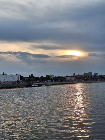 A sunset over a river with boats, a bridge, and buildings in the background. 2