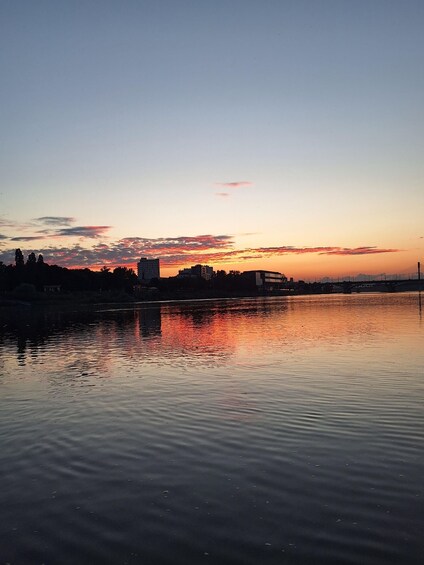 A sunset over a calm river with buildings silhouetted against the sky. 5