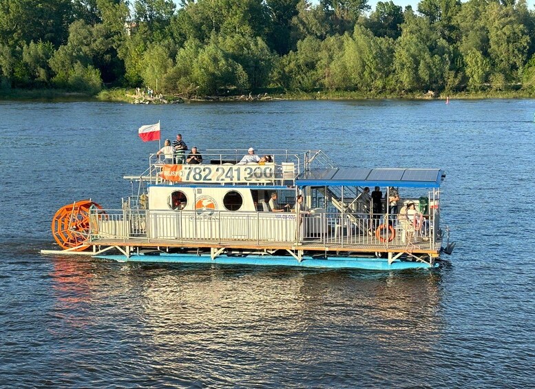 A riverboat with a flag, people on deck, and a forested shore in the background. 1