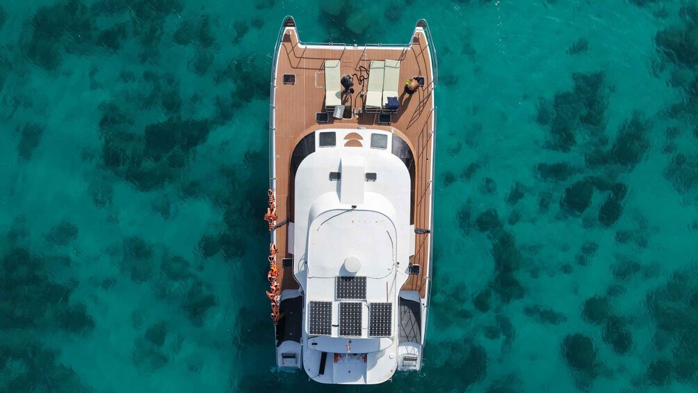 An aerial view of a boat with a cabin and lounge area, surrounded by clear turquoise water. 5