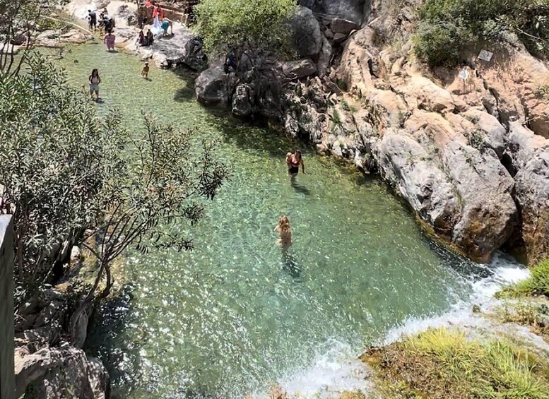 A clear river with people swimming and walking along the banks. 5