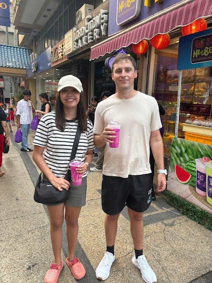 Two people standing in front of a bakery and a noodle house. 1