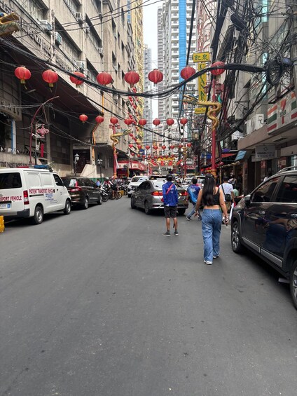 A busy street with red lanterns, vehicles, and pedestrians. 4