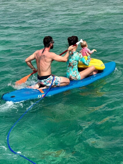A man and a child on a blue paddleboard in the water. 2