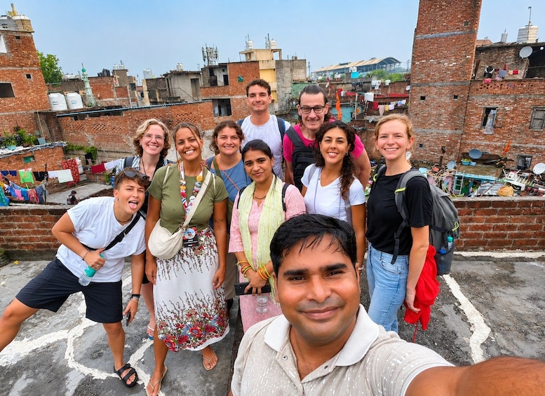 A group of people on a rooftop with brick buildings and satellite dishes in the background. 2
