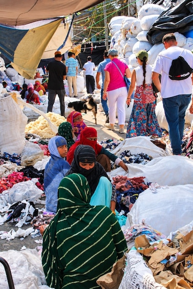 A bustling market with people sorting through piles of textiles and bags. 5